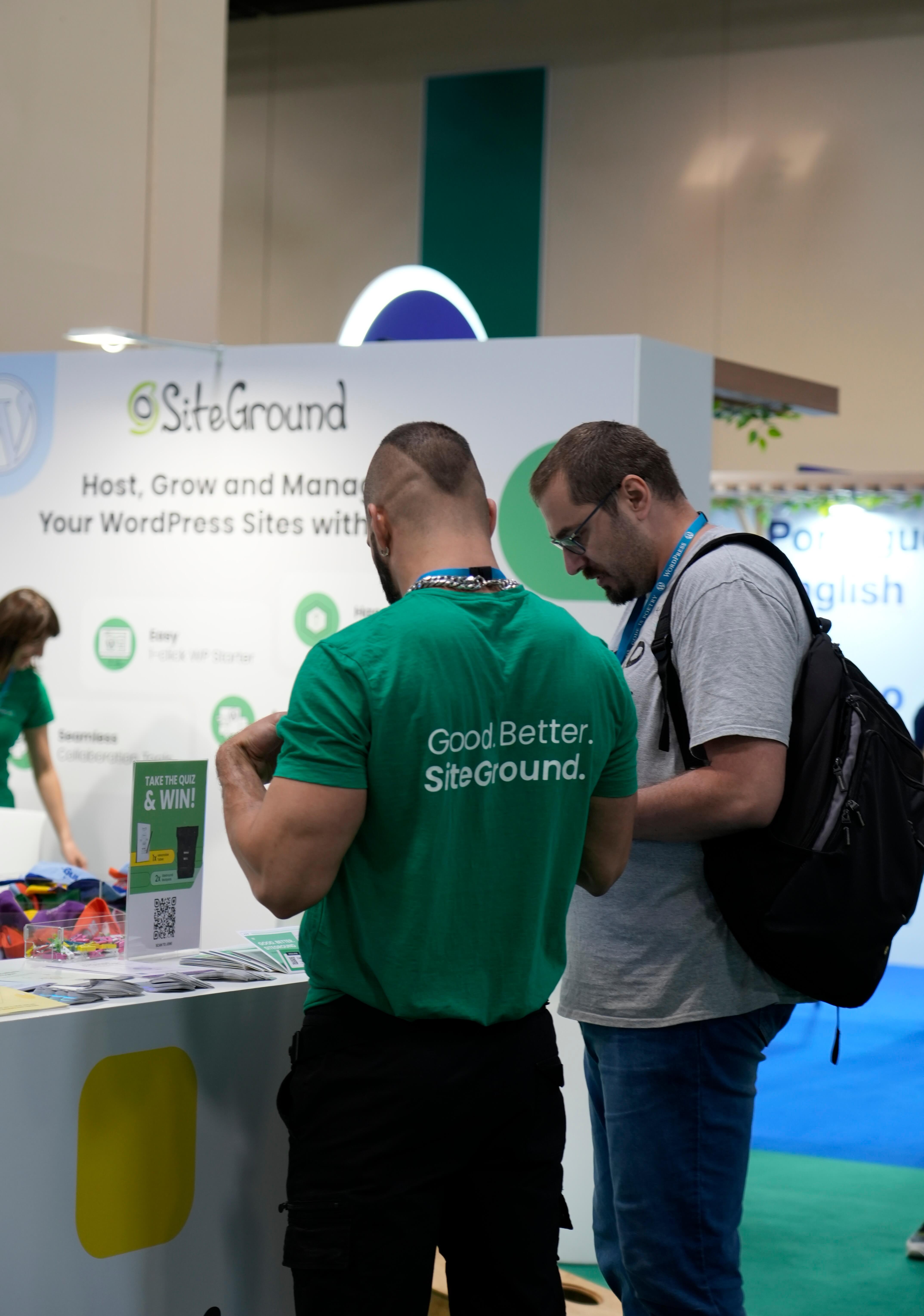 Foto dello stand di SiteGround al WordCamp Europe, dove due partecipanti stanno parlando fra loro.